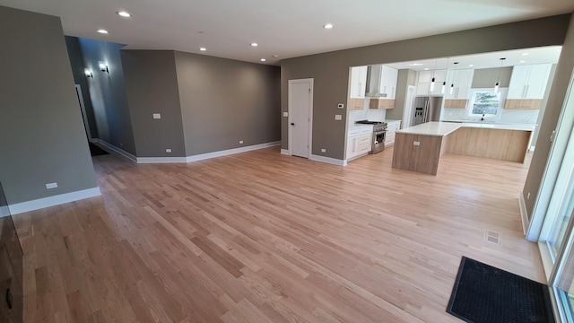 unfurnished living room featuring light wood-style flooring, recessed lighting, baseboards, and visible vents