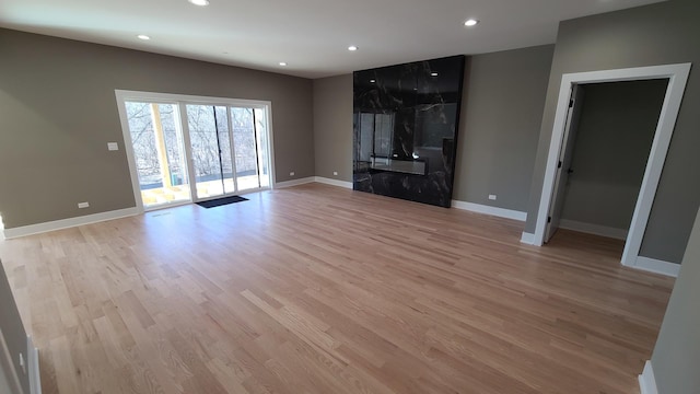 unfurnished living room with baseboards, light wood-type flooring, and recessed lighting