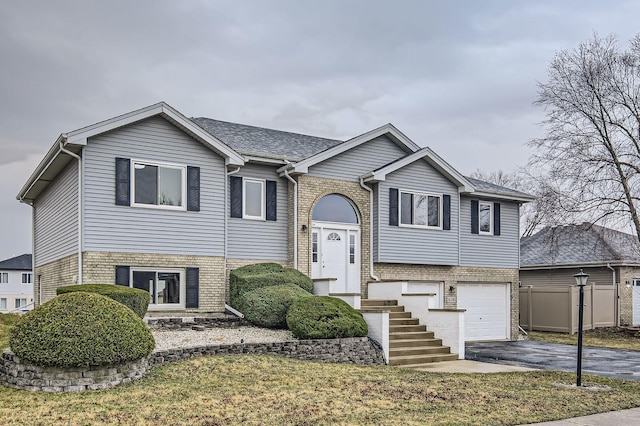 split foyer home featuring an attached garage, aphalt driveway, and brick siding