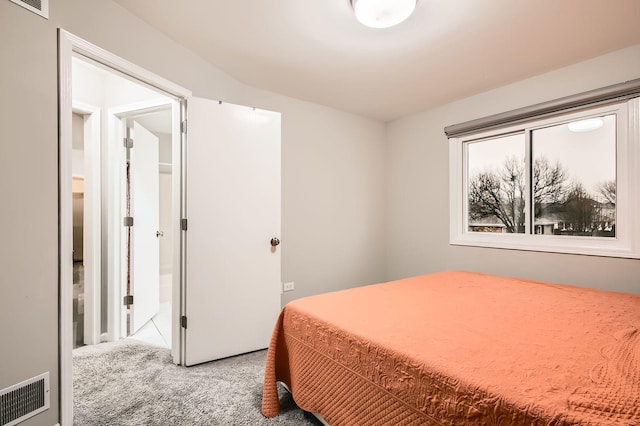 carpeted bedroom with visible vents and ensuite bathroom