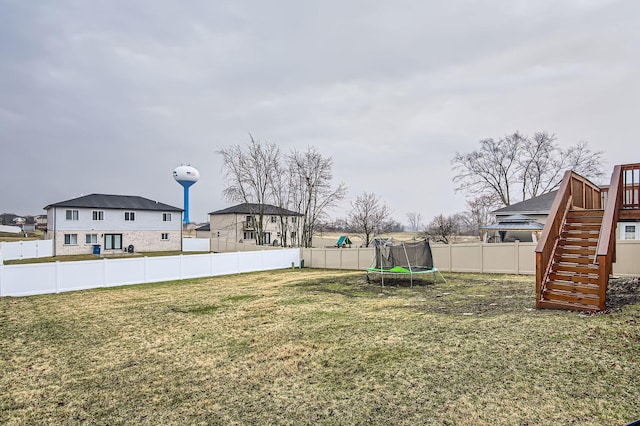 view of yard featuring a fenced backyard, stairway, and a trampoline