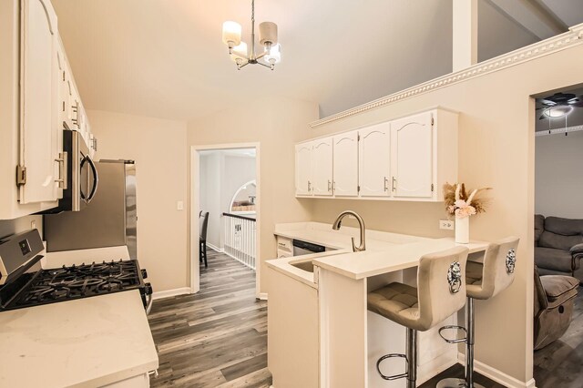 kitchen featuring light countertops, a chandelier, white cabinetry, wood finished floors, and stainless steel appliances