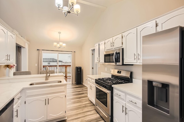 kitchen with white cabinets, a chandelier, stainless steel appliances, lofted ceiling, and a sink