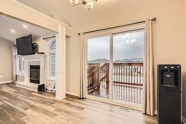 living area featuring wood finished floors, a tile fireplace, baseboards, and visible vents