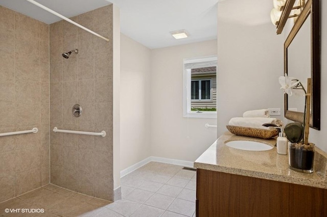 full bathroom with a tile shower, tile patterned floors, double vanity, and baseboards