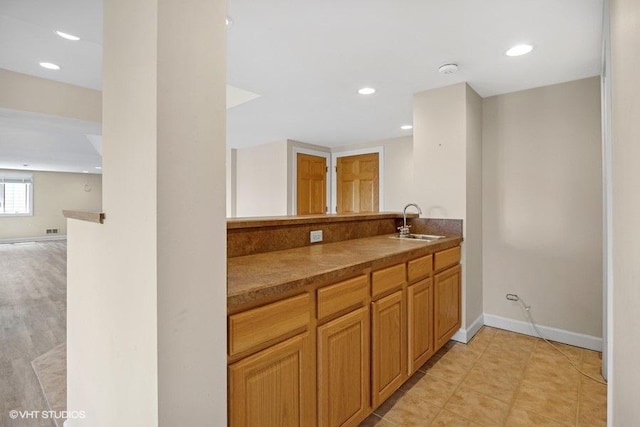 kitchen featuring a sink, baseboards, recessed lighting, open floor plan, and dark countertops