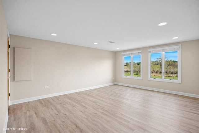 spare room featuring light wood-style flooring, recessed lighting, and baseboards