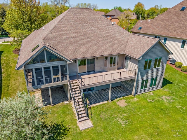 rear view of house with roof with shingles, a yard, a sunroom, and stairway