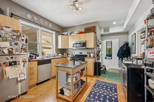 1943 N Whipple St, Chicago, IL 60647 - kitchen with appliances with stainless steel finishes, light brown cabinetry, light wood-style flooring, and healthy amount of natural light