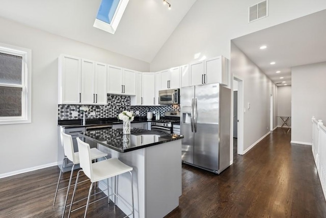 1540 E 65th Pl Unit 3, Chicago, IL 60637 - kitchen with a kitchen island, white cabinetry, appliances with stainless steel finishes, dark countertops, and visible vents
