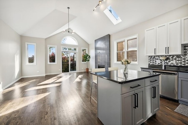 1540 E 65th Pl Unit 3, Chicago, IL 60637 - kitchen with dishwasher, dark countertops, dark wood finished floors, open floor plan, and lofted ceiling with skylight