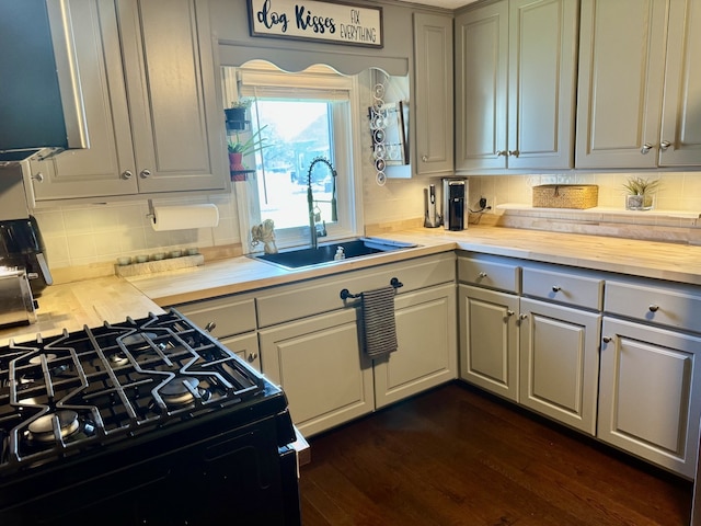 kitchen featuring gray cabinetry, a sink, dark wood-type flooring, and tasteful backsplash