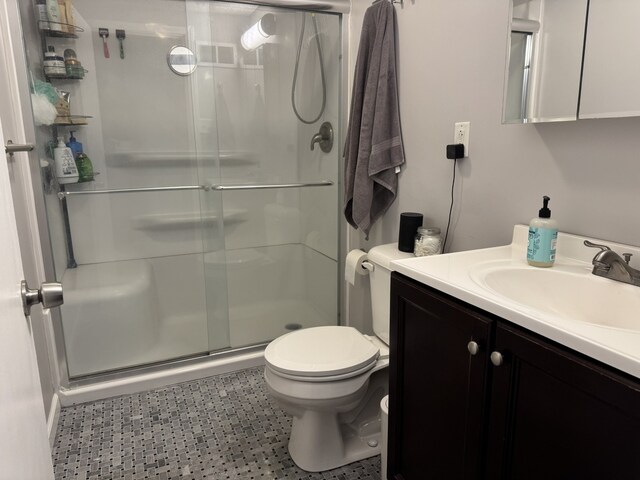 bathroom featuring toilet, vanity, and a stall shower