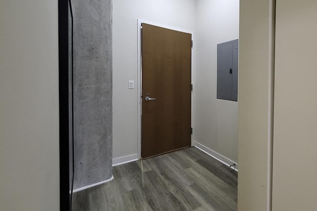 hallway featuring baseboards, wood finished floors, and electric panel