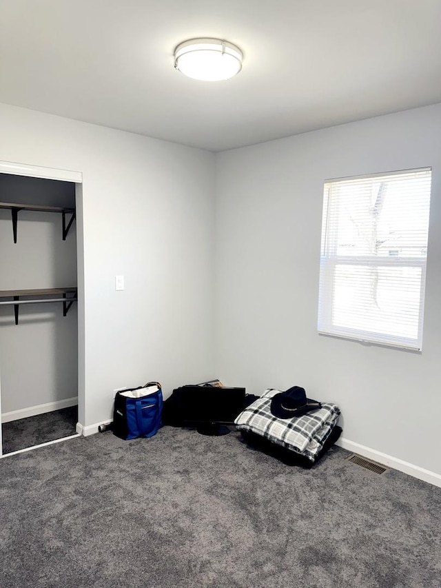 unfurnished bedroom featuring baseboards, carpet, a closet, and visible vents