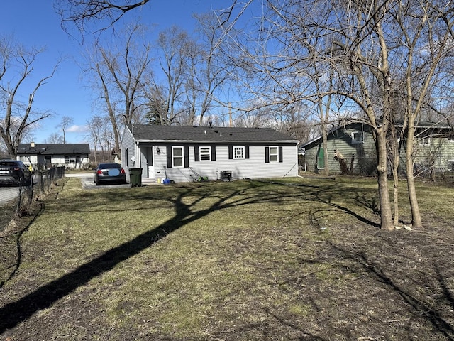 view of front facade with a front lawn, roof with shingles, and entry steps