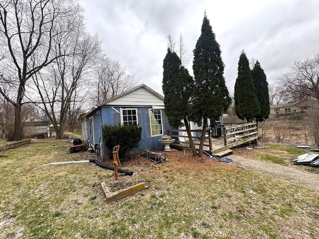 view of side of home featuring an outdoor structure, a deck, and a lawn