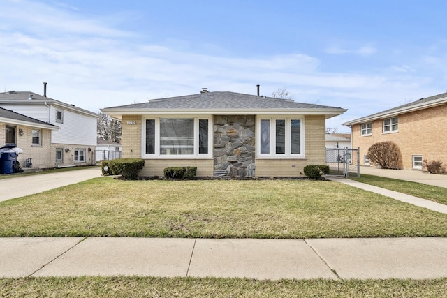 bungalow featuring roof with shingles, brick siding, fence, and a front lawn