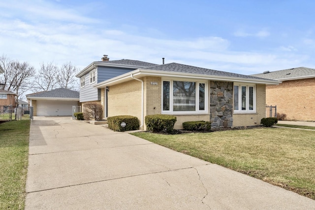 view of front of property featuring a front yard, a chimney, an outbuilding, brick siding, and a garage