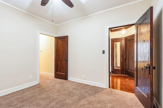 unfurnished bedroom featuring baseboards, ornamental molding, ceiling fan, and carpet