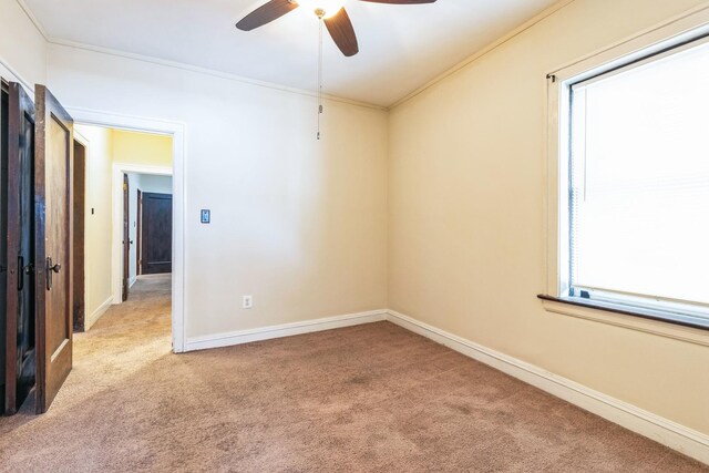 spare room with carpet flooring, a ceiling fan, ornamental molding, and baseboards