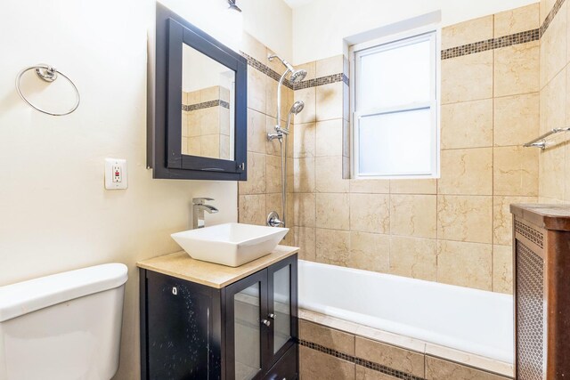 bathroom with toilet, tiled shower / bath, and vanity