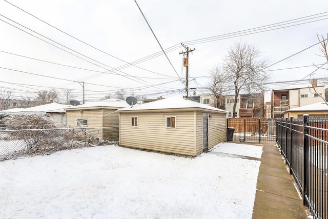 snow covered structure featuring an outbuilding and a fenced backyard