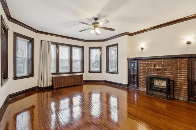 unfurnished living room with hardwood / wood-style flooring, baseboards, ceiling fan, a fireplace, and radiator heating unit