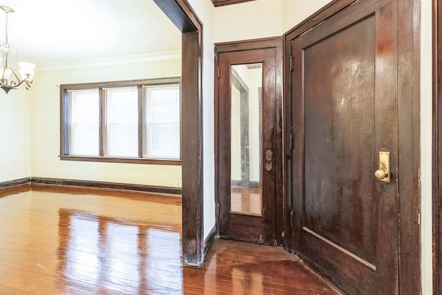 entrance foyer featuring baseboards, ornamental molding, a notable chandelier, and hardwood / wood-style flooring