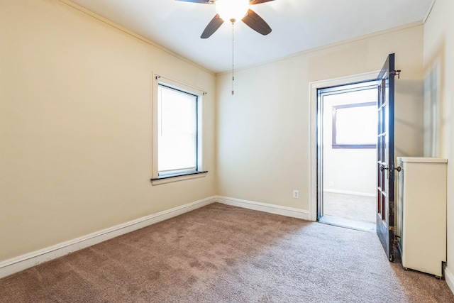 carpeted spare room featuring baseboards, ceiling fan, and ornamental molding