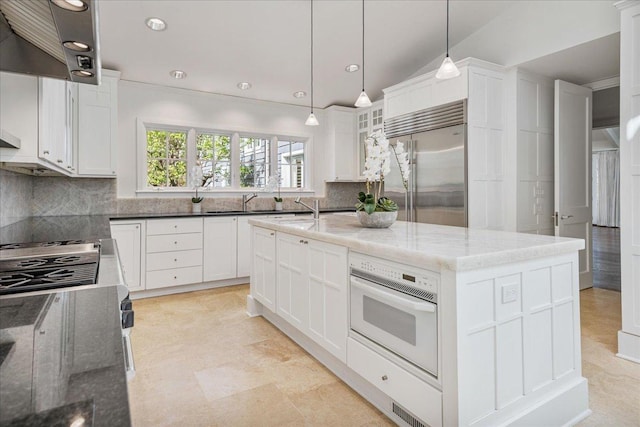 kitchen featuring appliances with stainless steel finishes, tasteful backsplash, dark stone countertops, and white cabinets