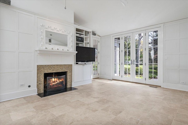unfurnished living room with vaulted ceiling, a fireplace with flush hearth, visible vents, and a decorative wall