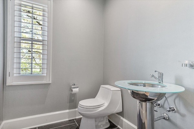 half bath with a healthy amount of sunlight, baseboards, and toilet