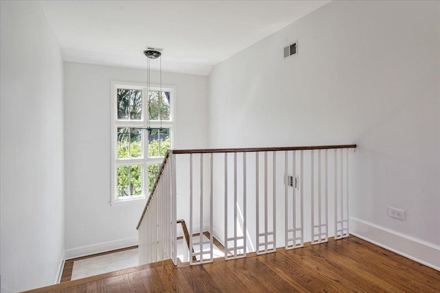 staircase with a healthy amount of sunlight, baseboards, wood finished floors, and visible vents