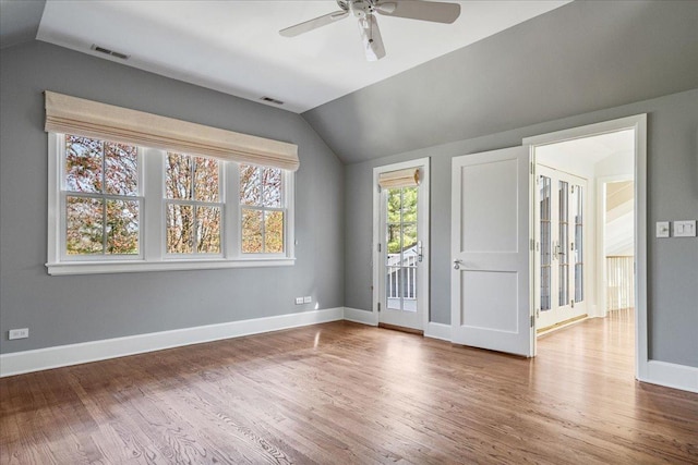 unfurnished bedroom with baseboards, vaulted ceiling, wood finished floors, and access to exterior