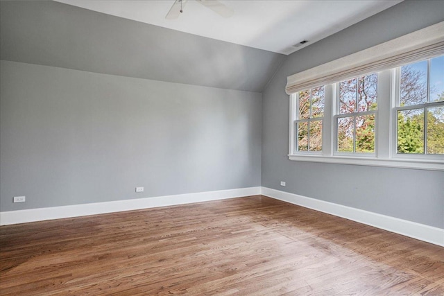 spare room with baseboards, ceiling fan, vaulted ceiling, and wood finished floors