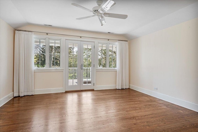 empty room with visible vents, baseboards, wood finished floors, and vaulted ceiling