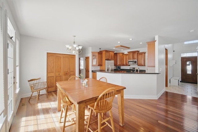 dining area with baseboards, light wood-style flooring, an inviting chandelier, and recessed lighting