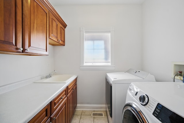 clothes washing area featuring visible vents, baseboards, a sink, washer and dryer, and cabinet space