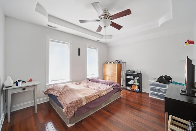 bedroom featuring hardwood / wood-style flooring, a ceiling fan, a raised ceiling, baseboards, and visible vents