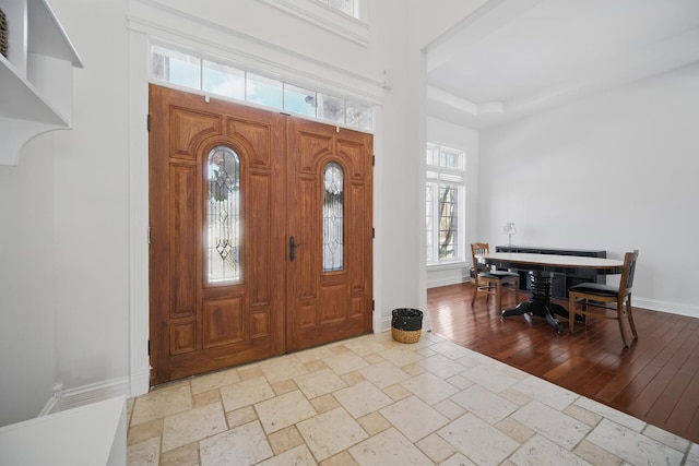 entryway with baseboards, stone tile floors, and a towering ceiling