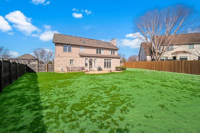 rear view of property with a fenced backyard, a chimney, a patio, and a yard
