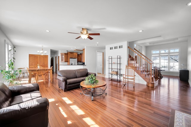 living room with ceiling fan with notable chandelier, light wood-type flooring, recessed lighting, and stairway