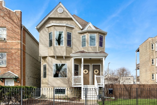 victorian house with a fenced front yard, a porch, and roof with shingles