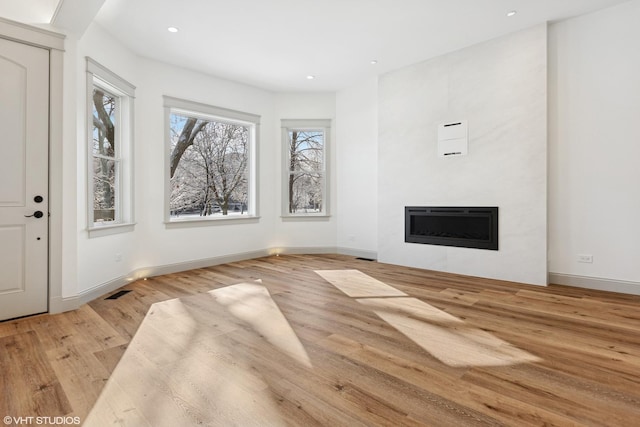 unfurnished living room featuring baseboards, a fireplace, light wood-style flooring, and recessed lighting