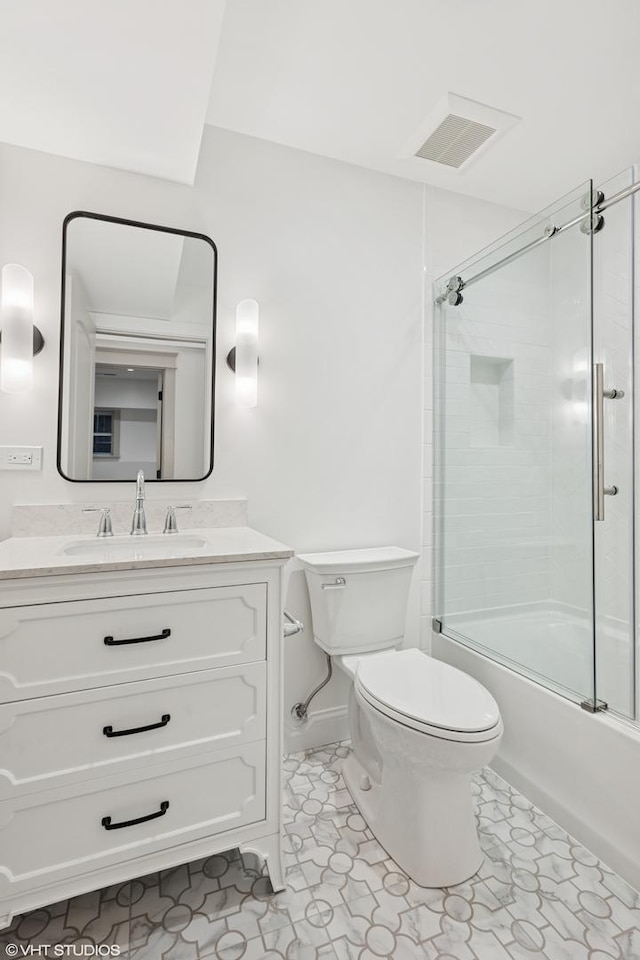 bathroom with vanity, toilet, bath / shower combo with glass door, and visible vents