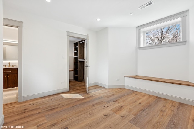 unfurnished bedroom featuring light wood-type flooring, visible vents, recessed lighting, a spacious closet, and baseboards