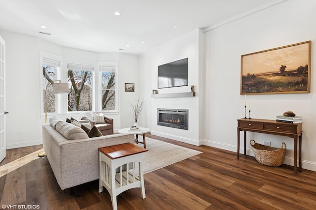 living area featuring recessed lighting, wood finished floors, baseboards, and a glass covered fireplace