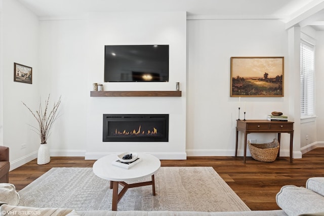 living room featuring baseboards, a glass covered fireplace, and wood finished floors