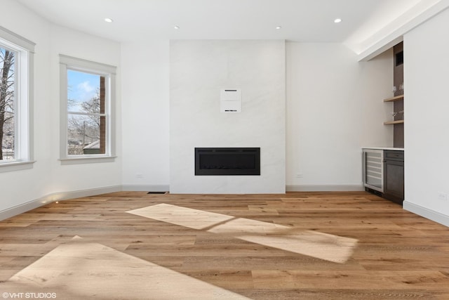unfurnished living room featuring wine cooler, a fireplace, light wood-style flooring, and recessed lighting
